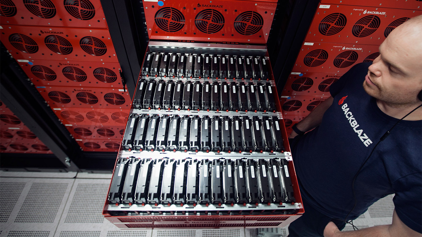 a tech standing looking at a pod full of hard drives in a data center