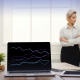 computer with line chart on a desk with a man and woman standing near it