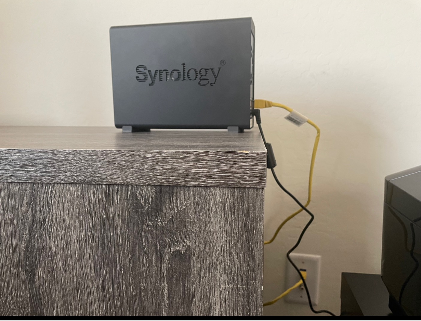 An image of a Synology NAS device set up on a desk and plugged into an ethernet connection.