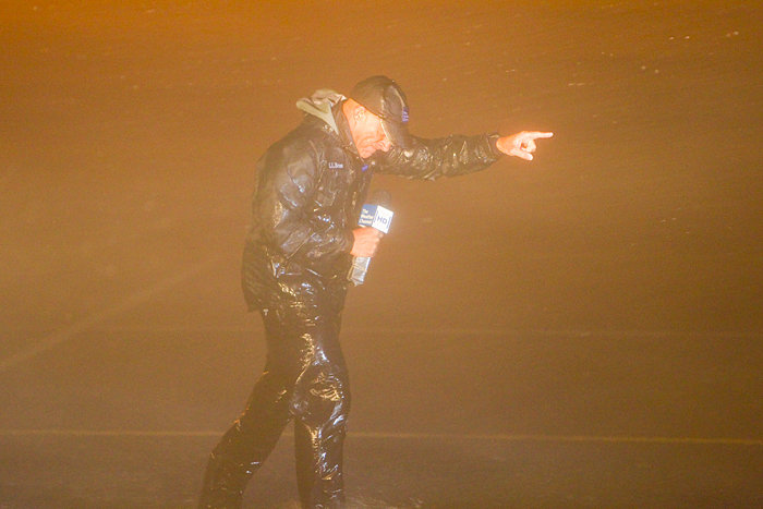 A photo of Jim Cantore in a storm pointing ahead.