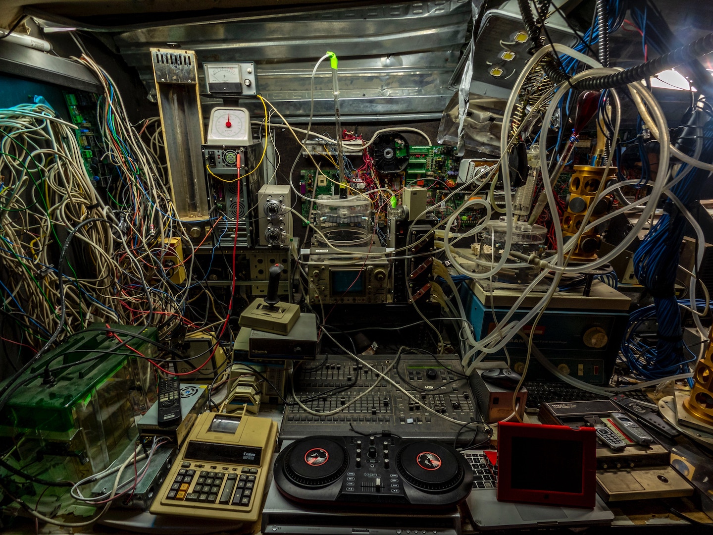 A photograph of a room with an overwhelming amount of old and new technology and cables. 
