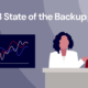 A decorative image featuring two figures behind a desk, a graph showing an upward trend line, and with the title "2023 State of the Backup".