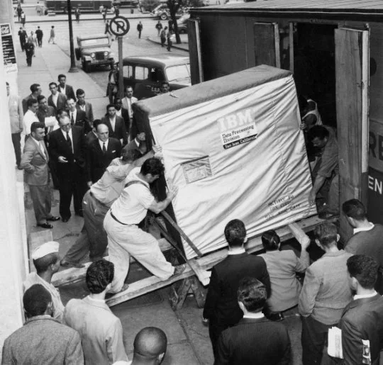 A photograph of people pushing one of the first hard disk drives into a truck.